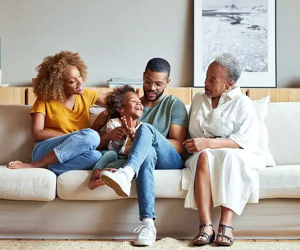 Famille multigénérationnelle assise ensemble sur un canapé et souriante.